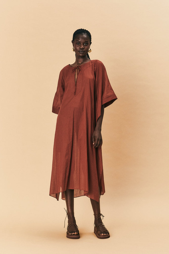 A young woman wearing La Maise Lia Kaftan dress in brown.