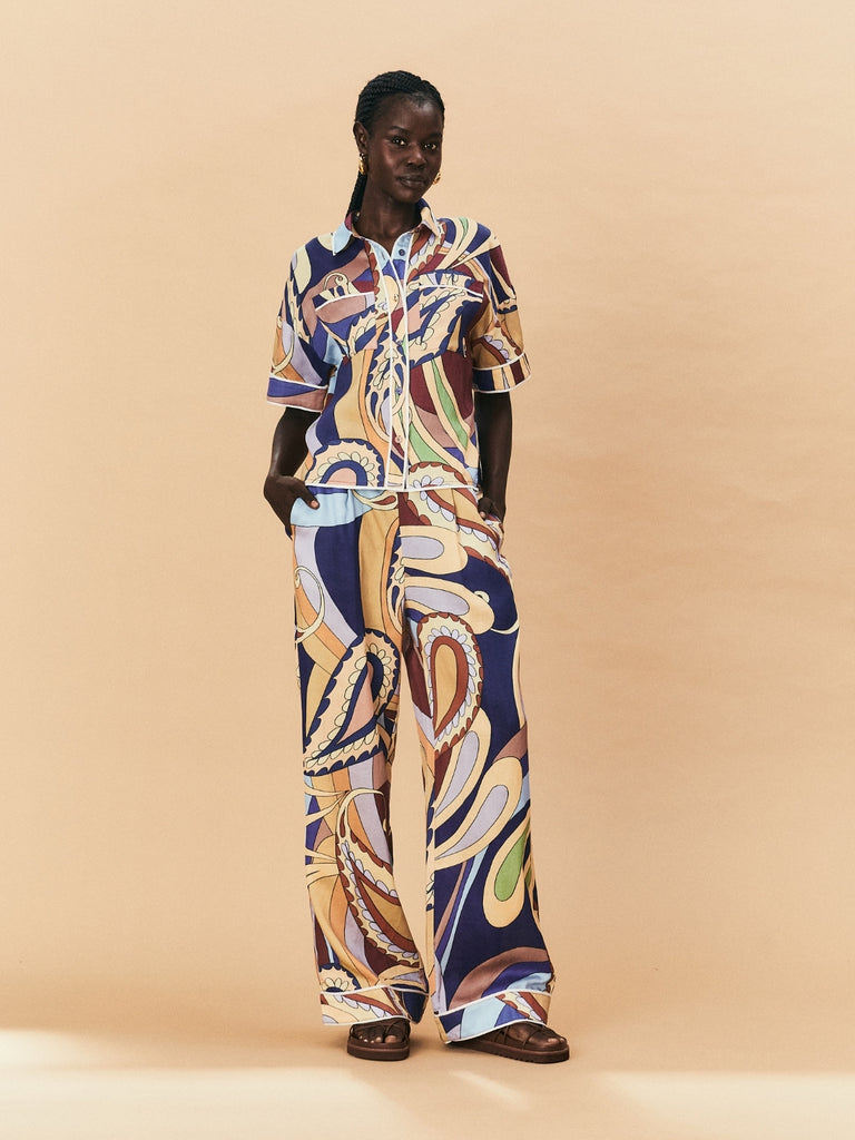 A woman wearing a La Maise Paisly Print Pant with a shirt standing against a beige background.