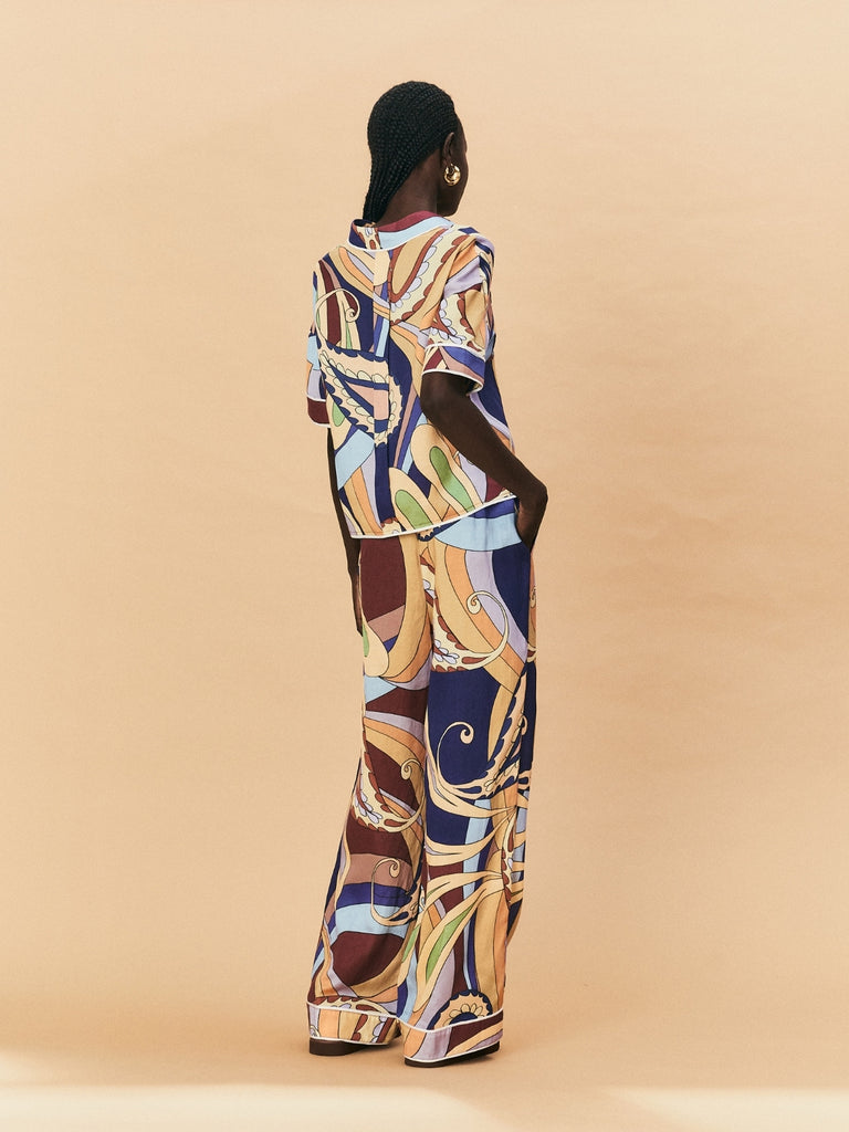 A woman wearing a La Maise Paisly Print Pant with a shirt standing against a beige background.