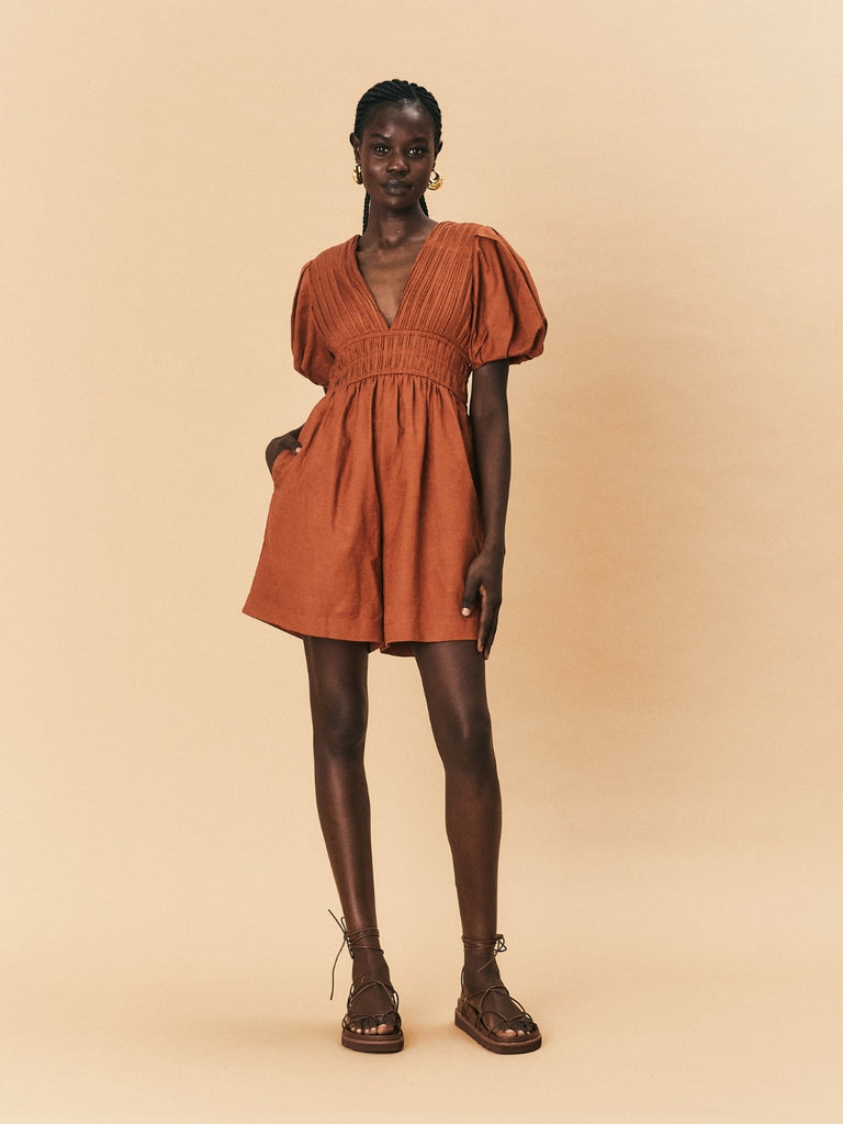 A young woman wearing La Maise Le Havre Romper in rust brown.