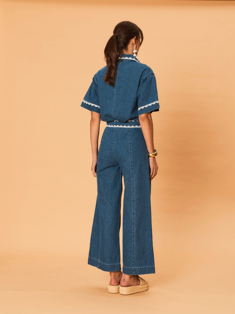 A woman wearing La Maise Ellie wide leg jean in indigo with lace trim on a beige background.