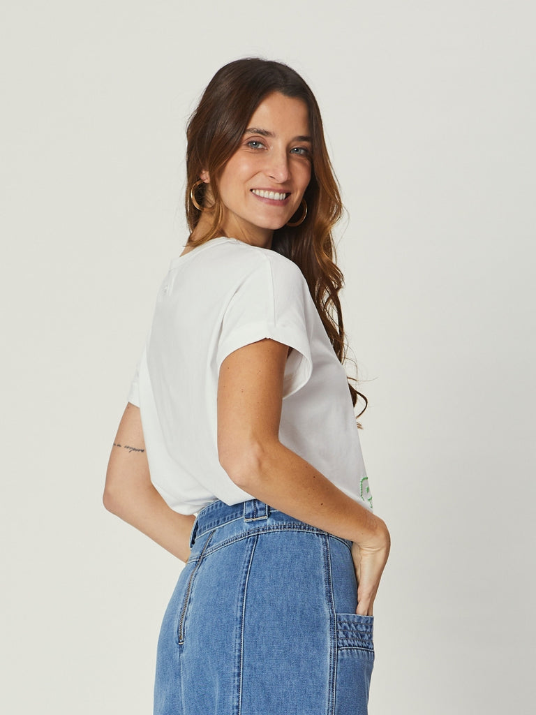 Woman wearing a white t-shirt and blue jeans against a plain background