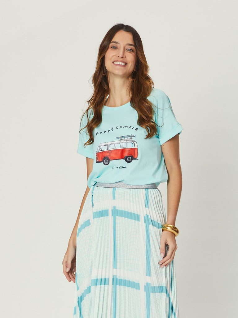 Woman wearing We Are the Others Jade Relaxed Tee – Happy Camper, a relaxed aqua graphic tee with retro camper van print, styled with a pleated skirt.