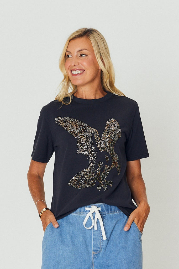 Woman wearing a black t-shirt with a graphic design and blue pants on a white background