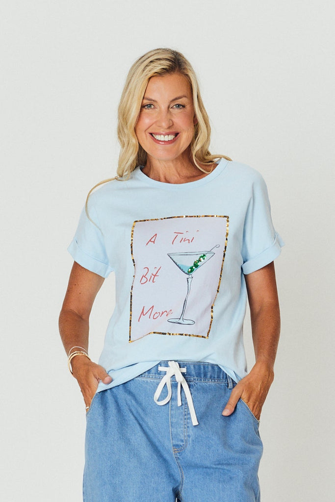 Woman wearing a light blue t-shirt and jeans standing against a white background