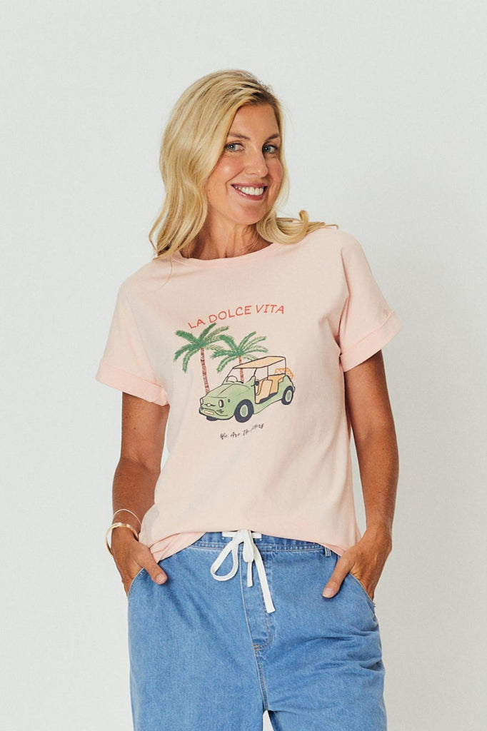 Woman wearing a pink t-shirt with a graphic design on a plain background