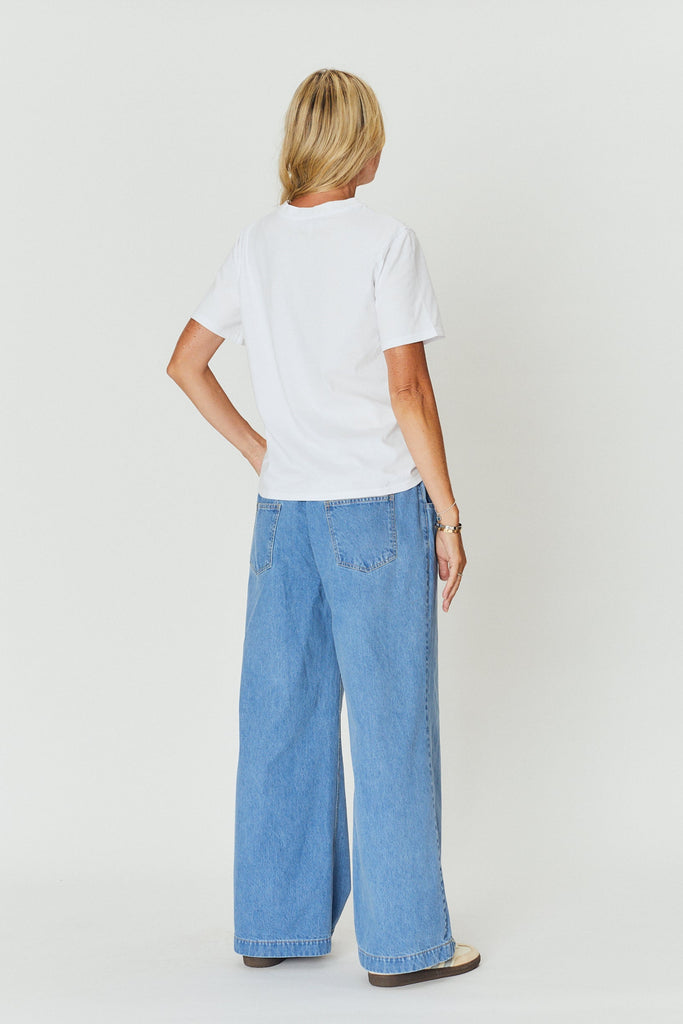 a woman wearing a white WATO tee with light blue denim.