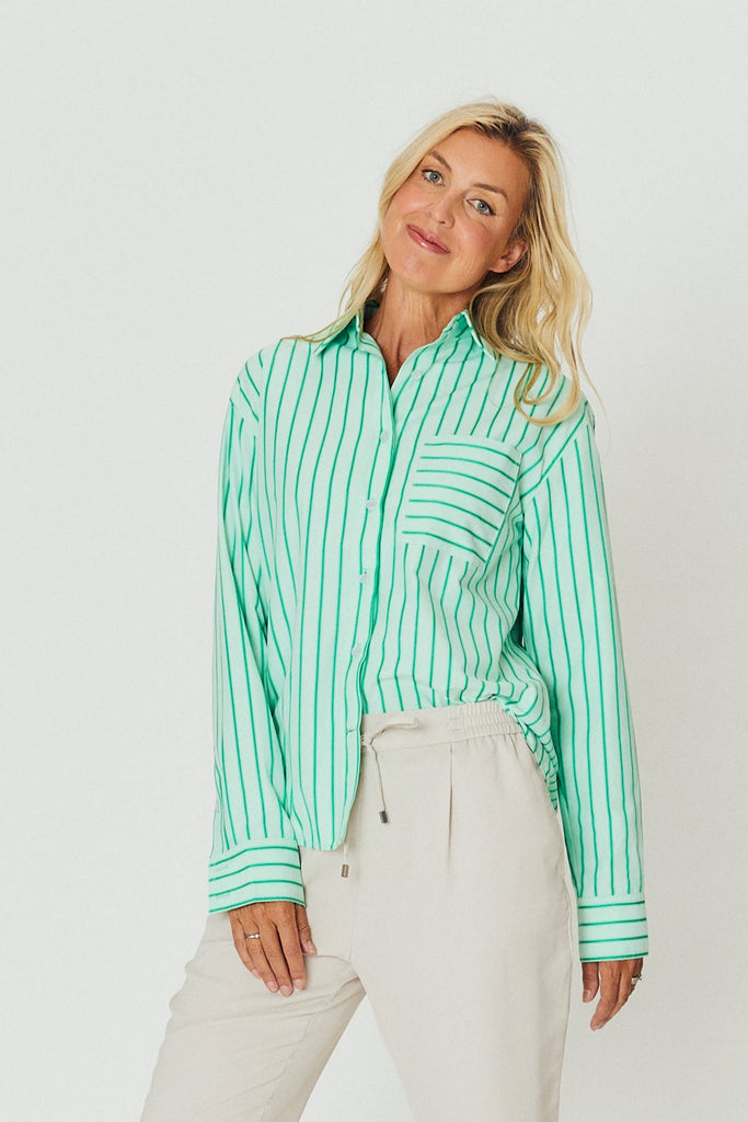 Woman wearing a green and white striped shirt against a plain background