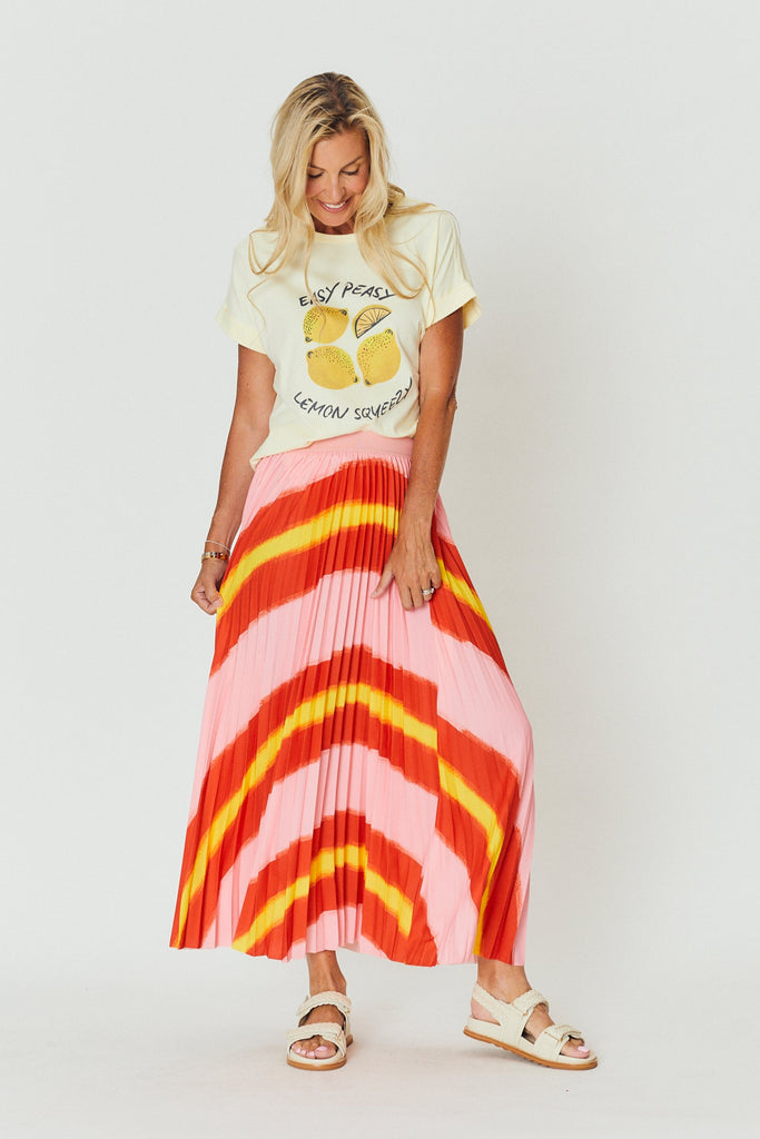 Woman wearing a graphic t-shirt and colorful skirt on a white background