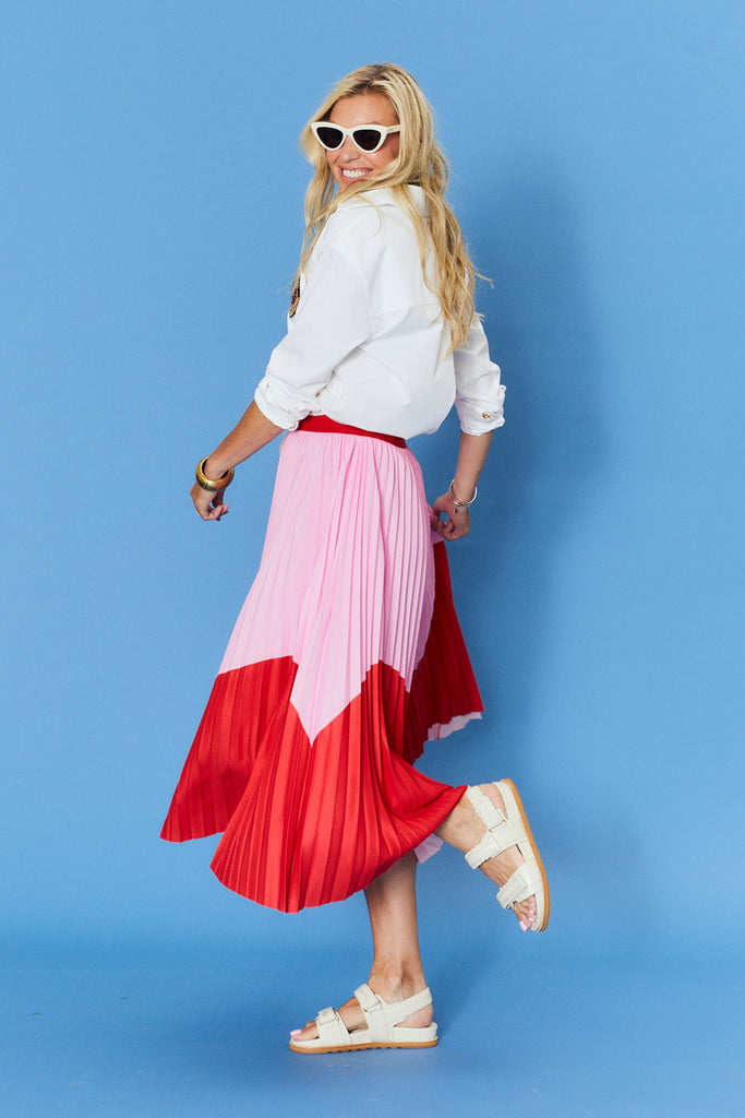Woman wearing a white shirt and red and pink gradient skirt against a blue background